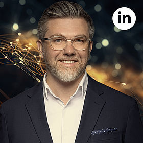 Prof. Dr. Ali Sunyaev mit Brille lacht in die Kamera