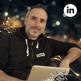 Rolf Hermann hinter einem Laptop, oben rechts das LinkedIn-Logo