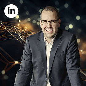 Johannes Keller im Anzug lächelt in die Kamera, oben links das LinkedIn-Logo