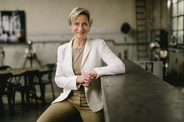 Dr. Nicole Hoffmeister-Kraut lächelnd neben einer Bar auf die sie den Arm lehnt