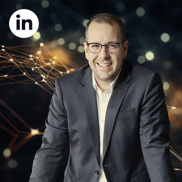 Vorsitz der AI Communication Award Jury Johannes Keller Johannes Keller im Anzug lächelt in die Kamera, oben links das LinkedIn-Logo